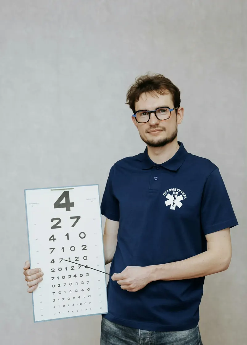 Maciej Wróblewski, optometrysta z Chojnic, z tablicą do badania ostrości wzroku